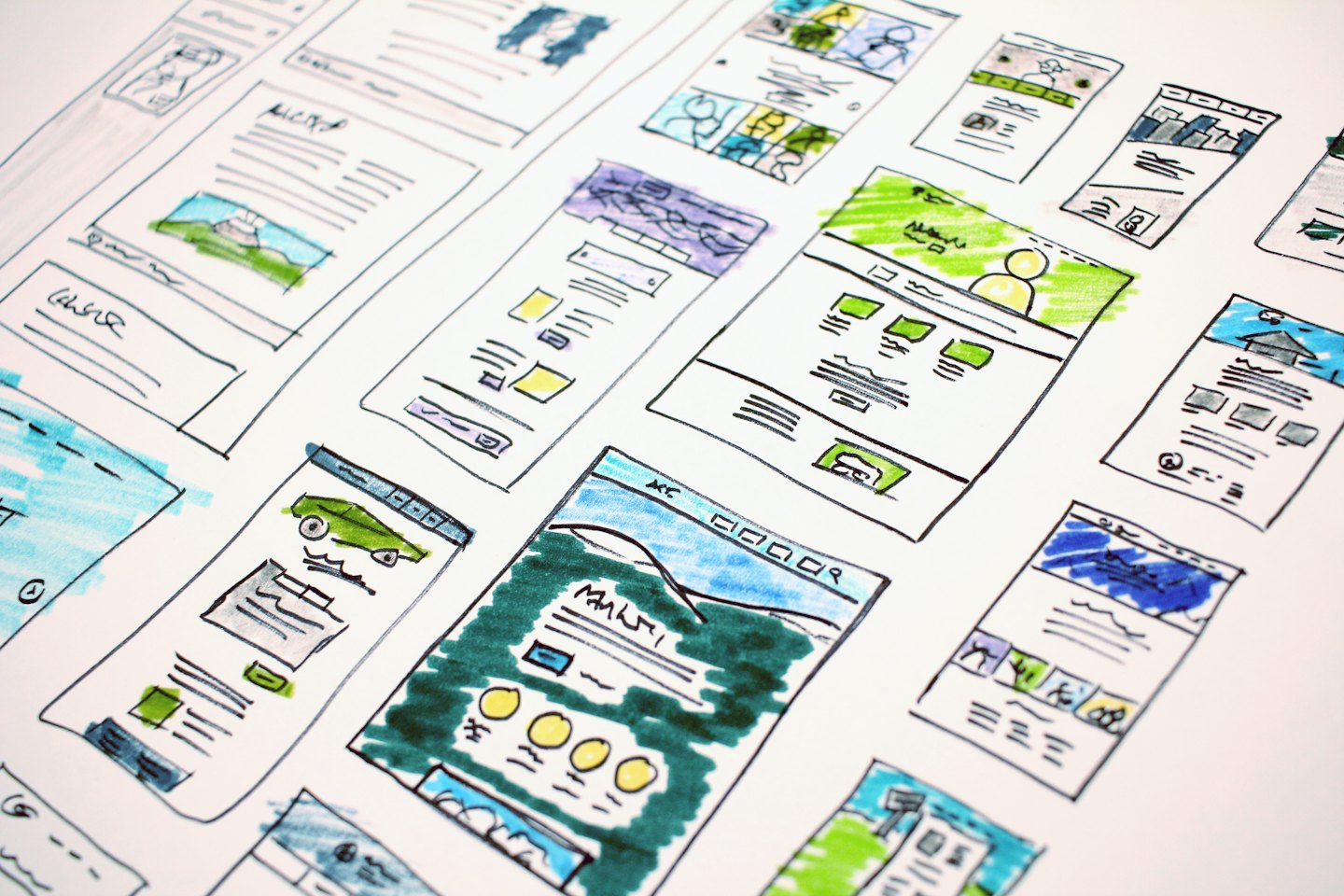 Hand-drawn website wireframes scattered across a white desk.